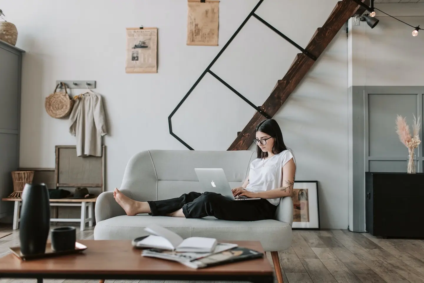 A woman sitting on a sofa with a laptop in a bright living room